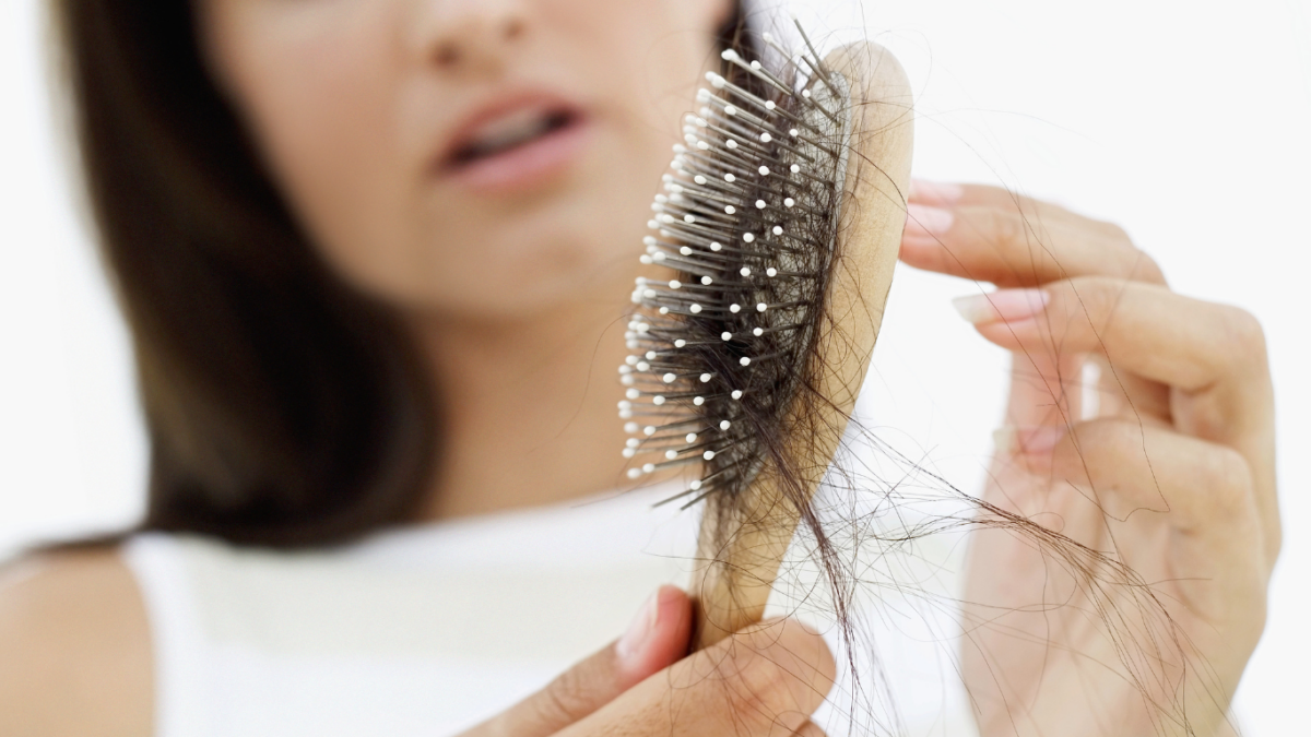 middle aged woman looking at her hair stands on brush