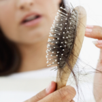 middle aged woman looking at her hair stands on brush