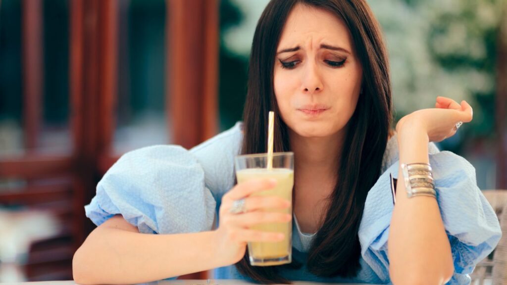 Woman Tasting Sour Lemonade Drink in a Restaurant