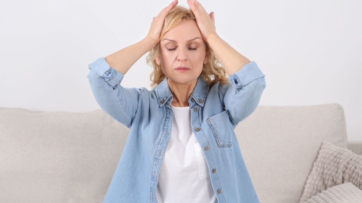 Woman Suffering from Headache on Sofa Indoors. Hormonal Disorder