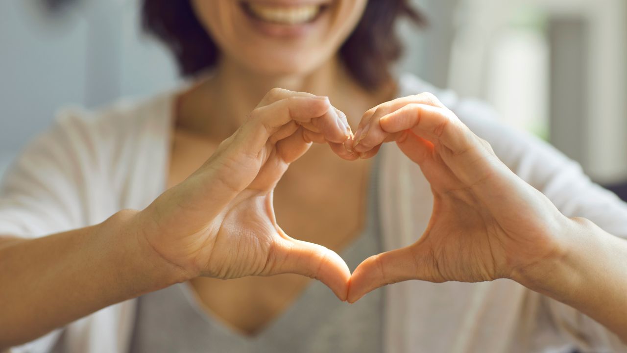 Cropped Shallow Focus Image of Happy Smiling Lady Showing Heart Symbol with Her Hands