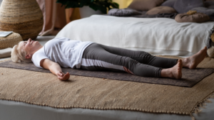 A mature woman lying on a yoga mat at home after gentle exercise during menopause recovery.