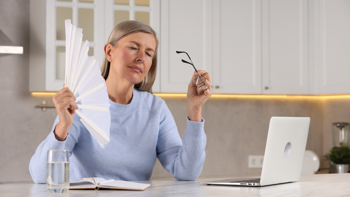 Woman experiencing a menopause hot flash while working on a laptop at home
